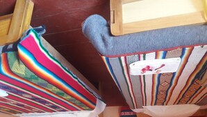 Una habitación con un marco de cama de madera, un edredón de colores y una alfombra con estampado rojo y beige.