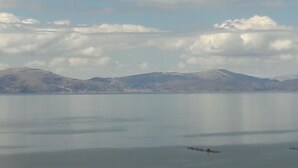 Un lago tranquilo con montañas al fondo y un pequeño bote en el agua.