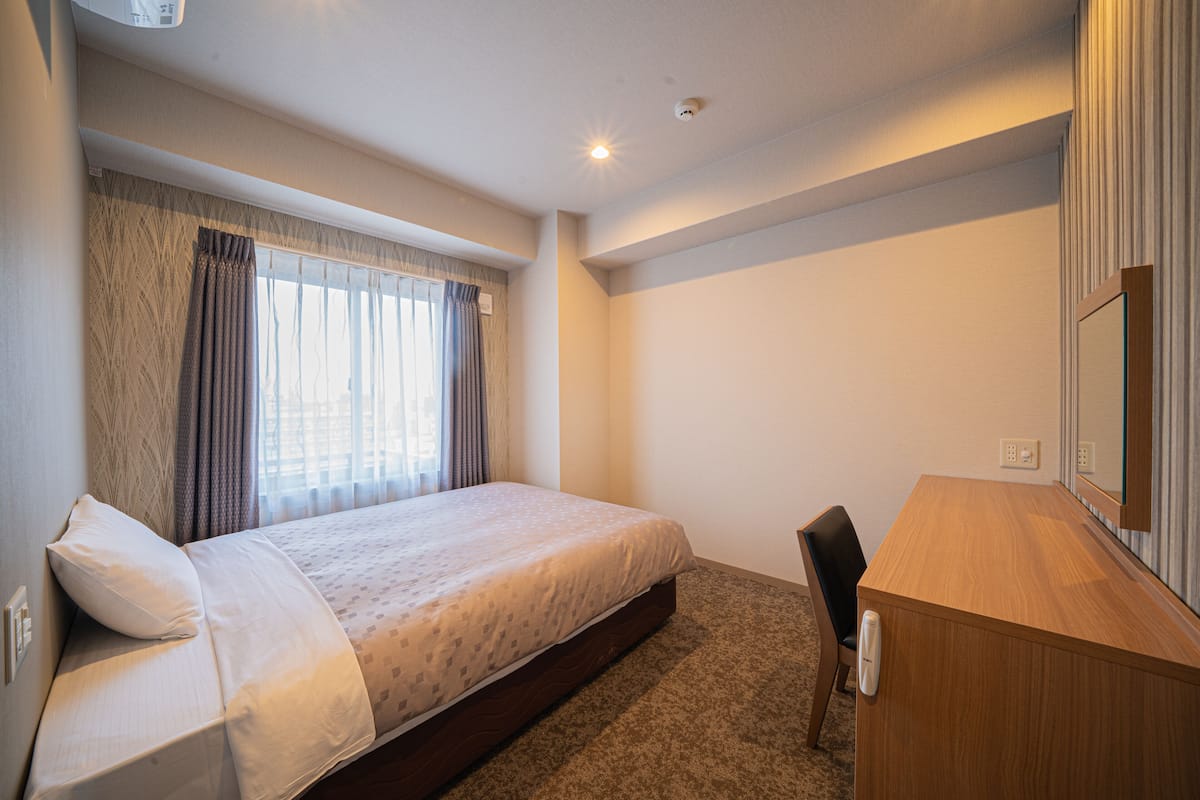 Una habitación de hotel con una cama, un escritorio y una silla.