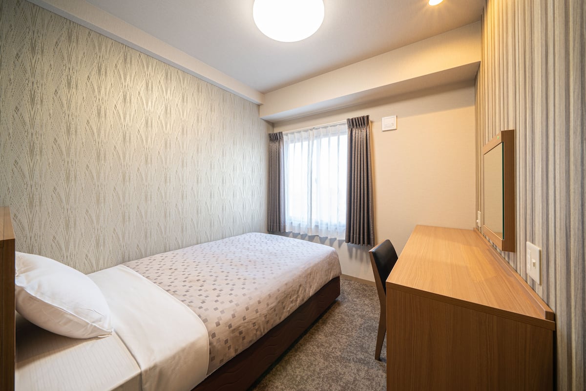 Una habitación de hotel con una cama, un escritorio y un espejo.