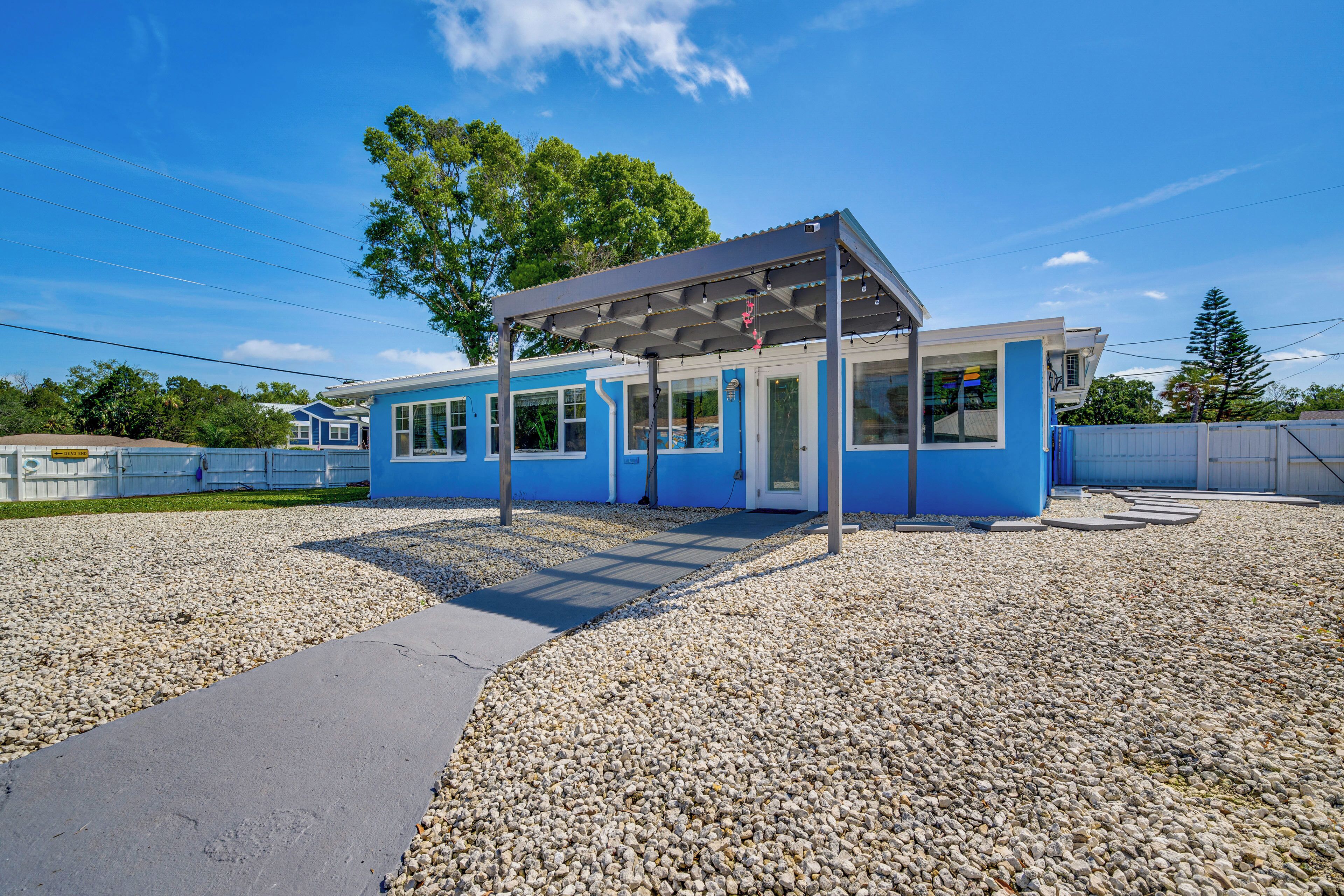 A modern building with a blue exterior, a covered outdoor area, and a gravel ground.