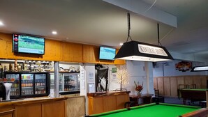 Een biljarttafel, een bar met een koelkast, en een bord met de tekst Kawerau Hotel.