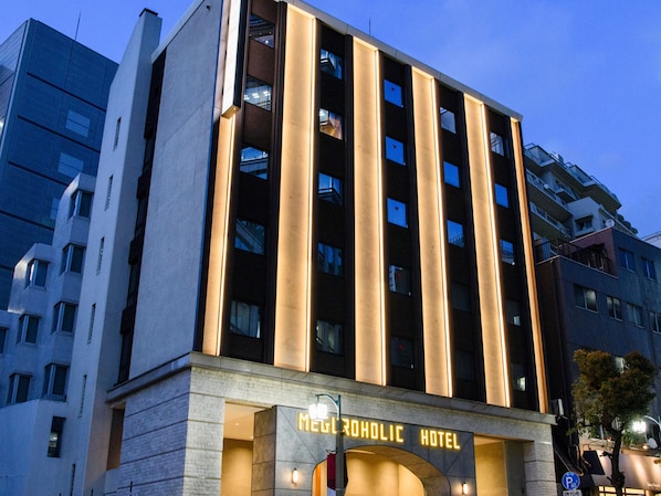 A modern hotel building with a prominent entrance and illuminated signage. - Meguro Holic Hotel (Tokyo)
