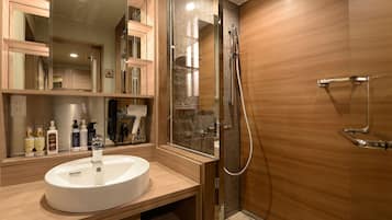 A modern bathroom with a wooden vanity, a large mirror, and a glass-enclosed shower area.