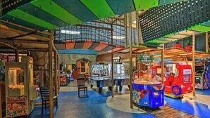 An indoor arcade with various gaming machines, a pool table, and a seating area.