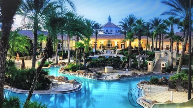 A resort with a large pool, palm trees, and a building with a dome roof.