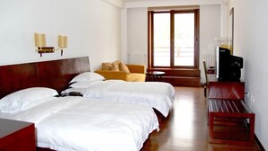 A hotel room with two beds, a sofa, a TV, and a window with a view. - Avaunce Yabuli Hotel (Harbin)