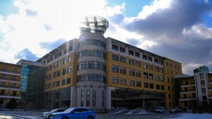 A multi-story building with a distinctive spherical structure on top, surrounded by other buildings. - Avaunce Yabuli Hotel (Harbin)