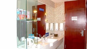 A hotel bathroom with a glass partition, a sink, a mirror, and a wooden door. - Avaunce Yabuli Hotel (Harbin)