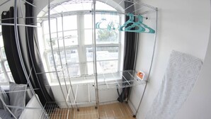 Una habitació amb un estenedor metàl·lic, una finestra amb cortines i una paret amb un disseny decoratiu.