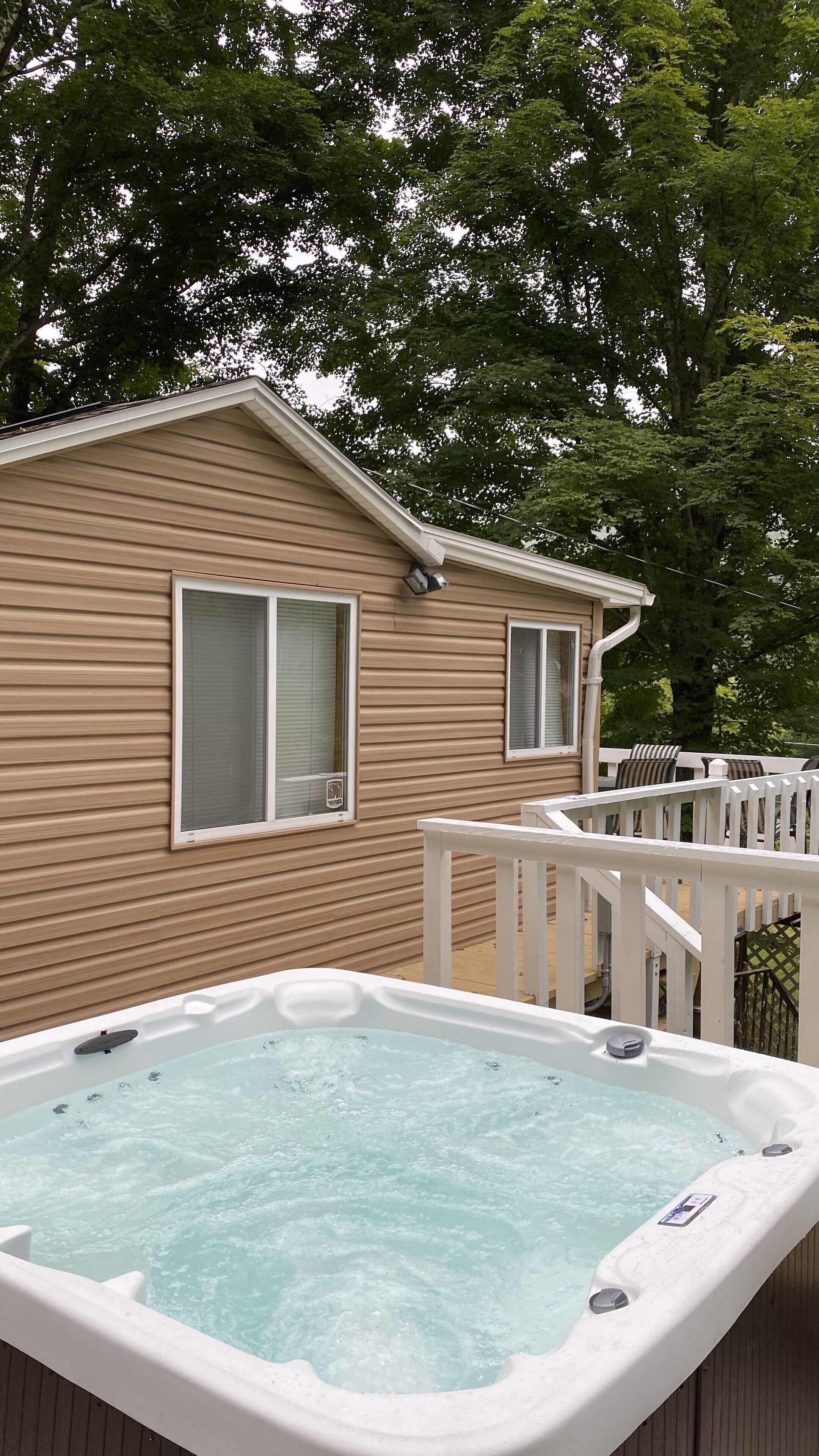 A house with a hot tub on a deck, surrounded by trees.