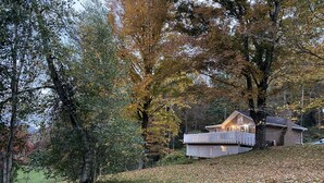 Une cabane dotée d’une terrasse, entourée d’arbres aux feuilles d’automne.