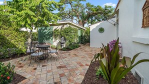 Une terrasse avec une table et des chaises, entourée de plantes et d’arbres.