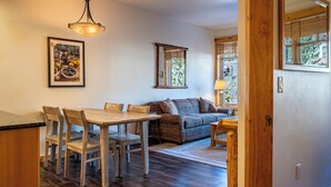 A cozy living area with a wooden dining table, chairs, a sofa, and a lamp. - Beautiful Views, Beautiful Condo , wifi, underground park, 1 minute to lifts (Copper Mountain)