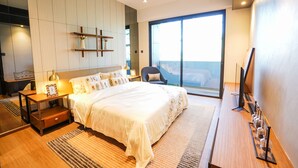 A modern bedroom with a large bed, a nightstand, a chair, and a TV. - 118 Residence (Bandar Seri Begawan)