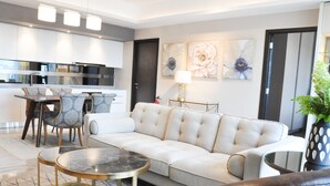 A modern living room with a sofa, dining table, chairs, and a kitchen area in the background. - 118 Residence (Bandar Seri Begawan)