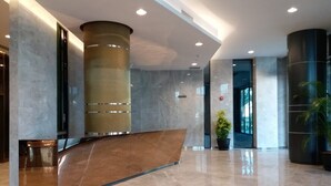 A modern lobby with a curved reception desk, large cylindrical columns, and a polished marble floor. - 118 Residence (Bandar Seri Begawan)