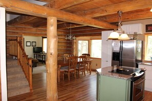 L’intérieur d’une cabane en rondins comprend un coin repas, une cuisine et un escalier menant à un autre niveau.