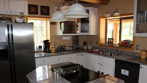 A kitchen with a stainless steel refrigerator, a built-in stove, granite countertops, and white cabinets. - The Gingerbread Cottage - 2.5 acres, craft or meeting room (Bailey)