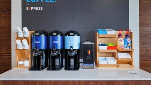 A coffee station with three coffee dispensers, a hot water dispenser, and a sign indicating hot water. - Holiday Inn Express & Suites Grand Rapids Airport - South by IHG (Grand Rapids)