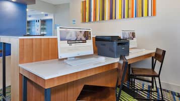 A hotel reception desk with a computer, printer, and a chair.