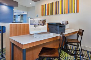 Una recepción de hotel con computadora, impresora y una silla.