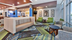 A hotel lobby with a sofa, chairs, a patterned carpet, and artwork on the walls. - Holiday Inn Express & Suites Grand Rapids Airport - South by IHG (Grand Rapids)
