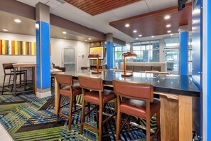 A modern bar area with a bar counter, stools, and a patterned rug. - Holiday Inn Express & Suites Grand Rapids Airport - South by IHG (Grand Rapids)