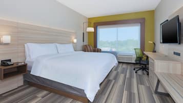 A hotel room with a bed, desk, chair, TV, and a large window.