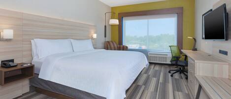 A hotel room with a bed, desk, chair, TV, and a large window.