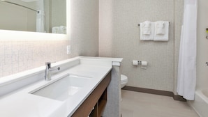 Un baño moderno con un espejo grande, lavamanos doble, inodoro y zona de ducha.