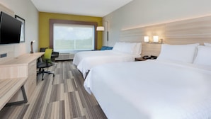 Habitación de hotel con dos camas, un escritorio, una silla, un televisor y un ventanal grande.
