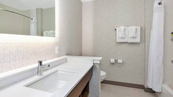Een moderne badkamer met een grote spiegel, een dubbele wastafel, toilet en een douchehoek.