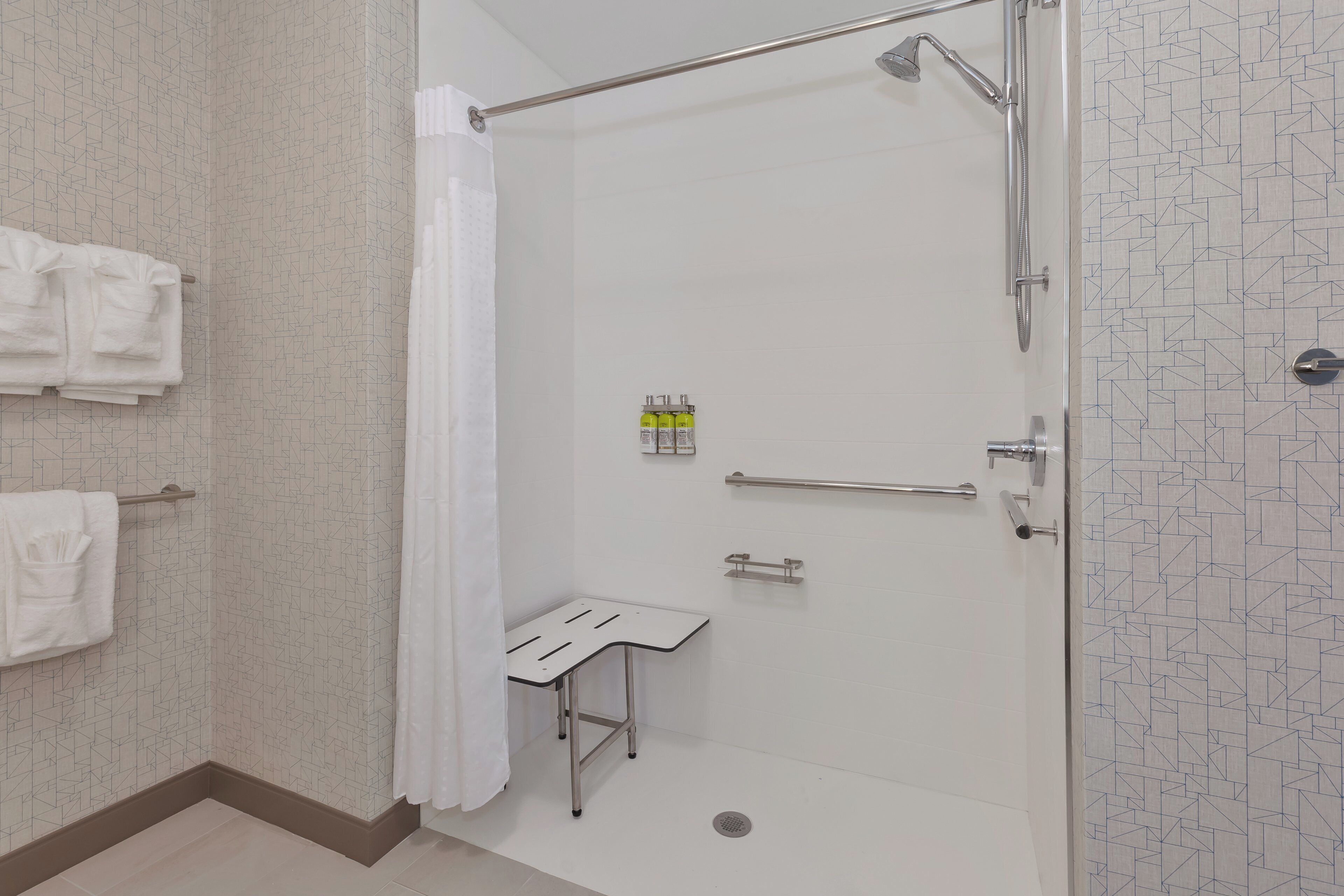 A shower with a glass door, a towel rack, and a small table with a towel.