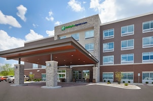 Edificio de Holiday Inn Express & Suites con entrada cubierta, pilares de piedra y estacionamiento.