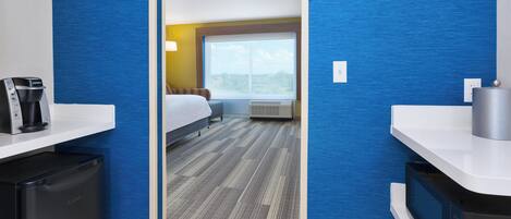 A hotel room with a bed, a window, a desk with a coffee maker, and a microwave.