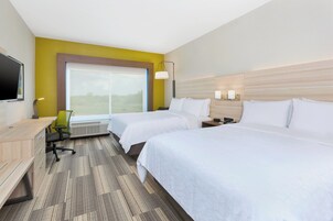 Una habitación de hotel con dos camas, un escritorio, una silla, un televisor y un ventanal grande.