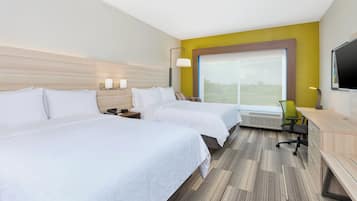 Habitación de hotel con dos camas, un escritorio, una silla, un televisor y un ventanal grande.