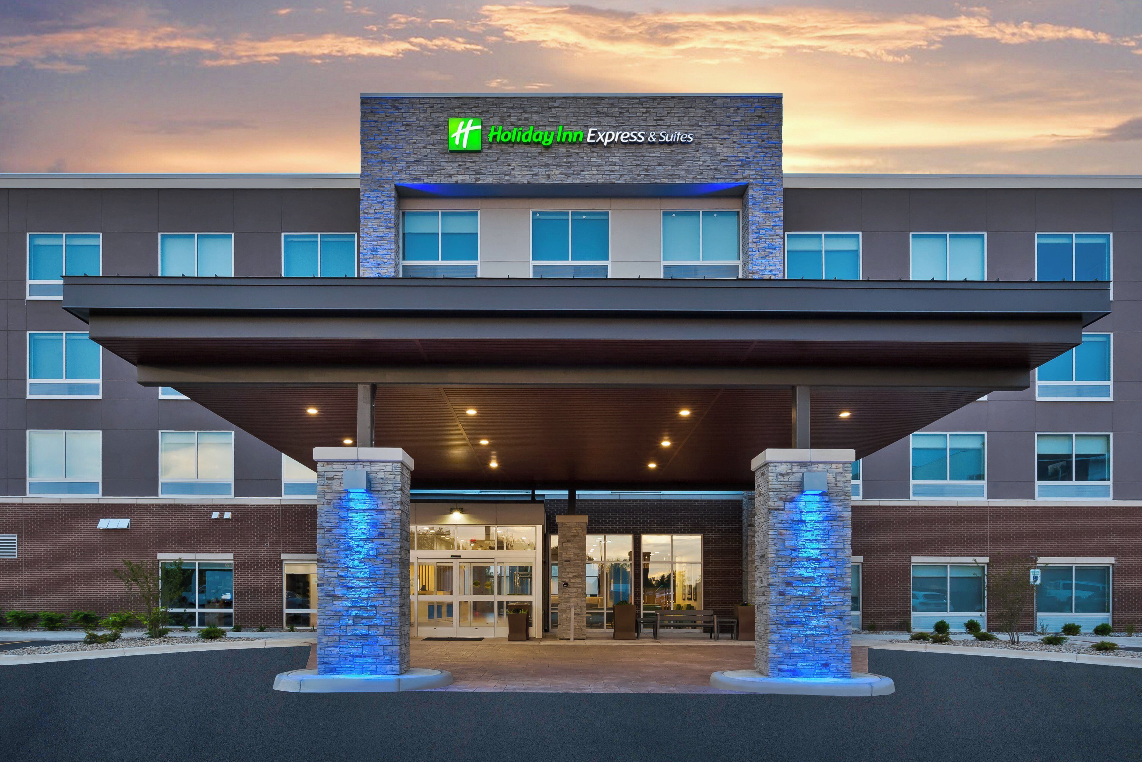 A Holiday Inn Express & Suites building with a modern design, featuring a stone facade and a covered entrance.