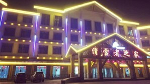 A multi-story hotel with illuminated neon lights outlining the structure. - Yabuli Skier Hotel (Harbin)