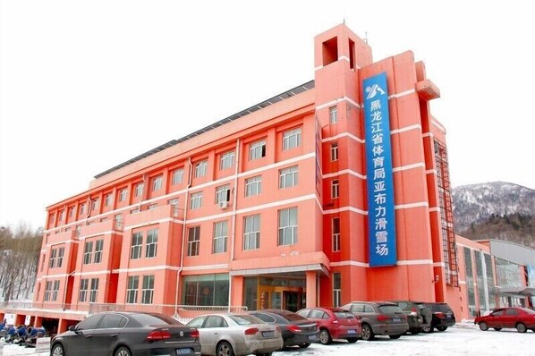 A multi-story building with a red facade and a blue vertical sign. - Yabuli Olympic Club Hotel (Harbin)