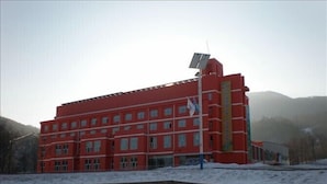 A red building with multiple windows and a solar panel on the roof. - Yabuli Olympic Club Hotel (Harbin)