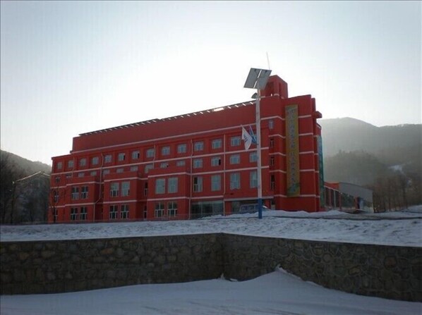Un bâtiment rouge doté de nombreuses fenêtres et d’un panneau solaire sur le toit.