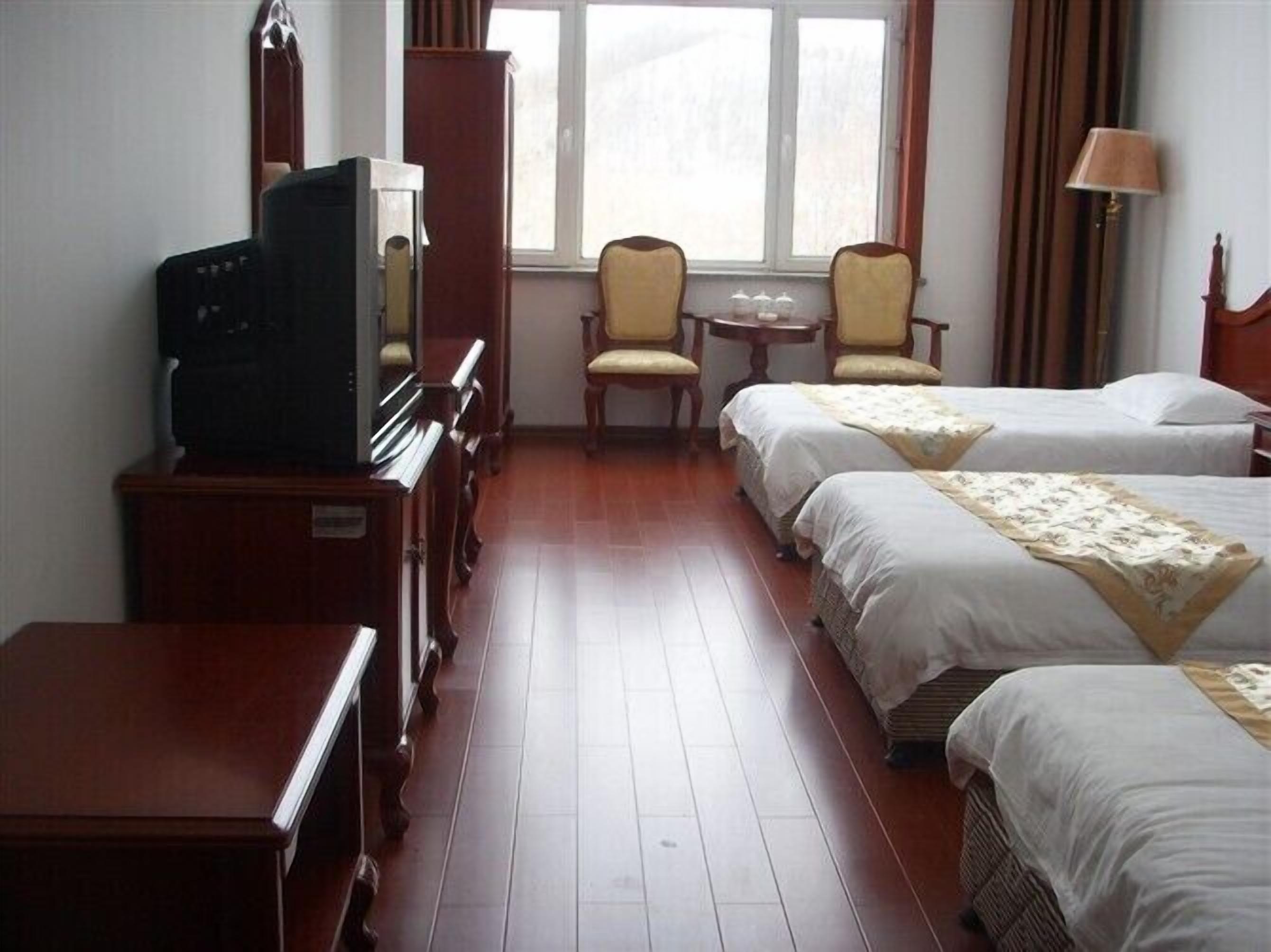 A hotel room with a piano, two single beds, a small table, and a chair.