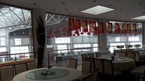 A restaurant with round tables and chairs, large windows, and red decorations. - Yabuli Olympic Club Hotel (Harbin)
