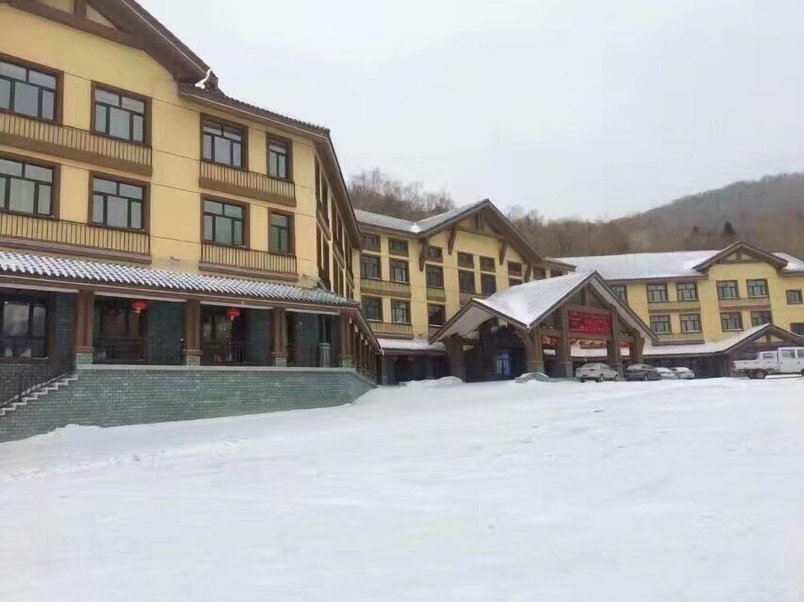 Een hotel met meerdere verdiepingen in traditionele bouwstijl, met balkons en een overdekte ingang.