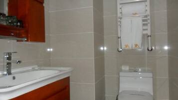 A bathroom with a sink, mirror, cabinet, toilet, and towel rack.