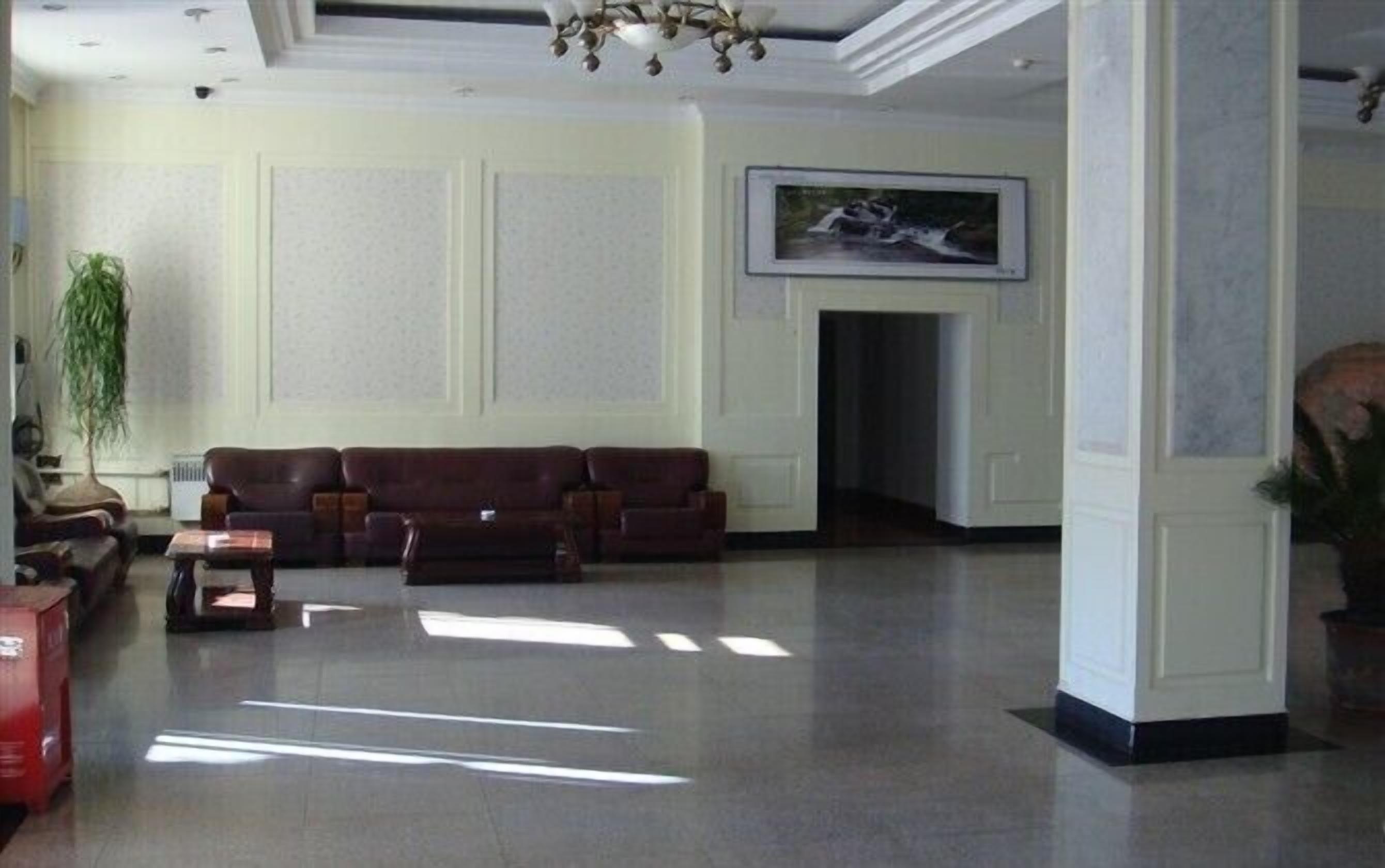 Un hall d’entrée spacieux, avec un canapé en cuir, une cheminée et un tableau encadré au mur.