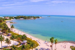 A beach with clear turquoise waters, palm trees, and beach umbrellas. - Luxury Waterfront DOCK 4/3 BEACH ICE MACHINE / PRIVATE POOL / HEATER/CHILLER (Marathon)