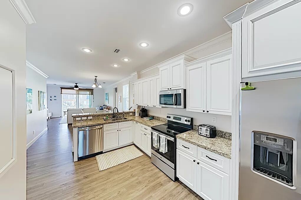 A modern kitchen with white cabinetry, stainless steel appliances, and a granite countertop.